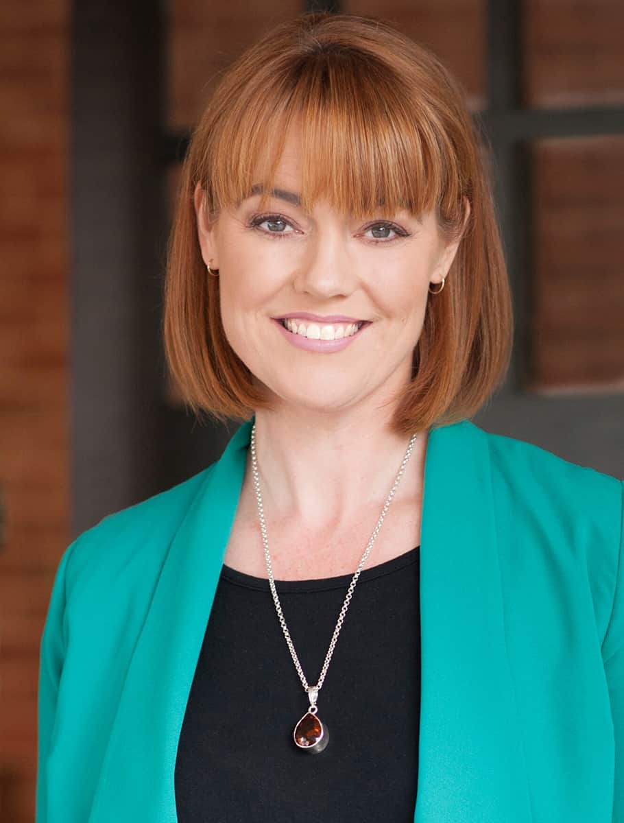 Kate Crocker, sales page copywriter, looking at camera and smiling, wearing a green jacket