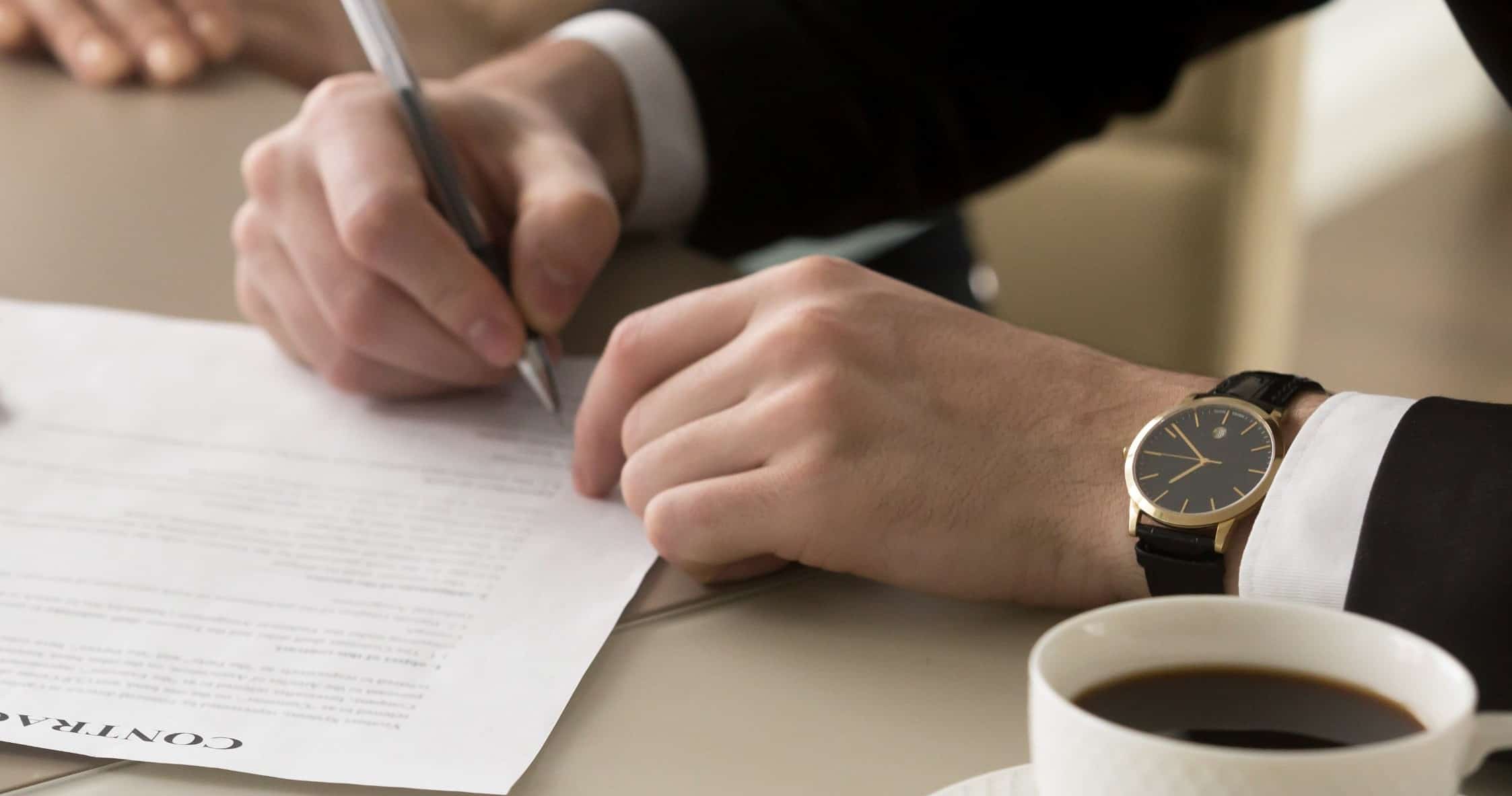 Man's hand holding pen, signing contract document